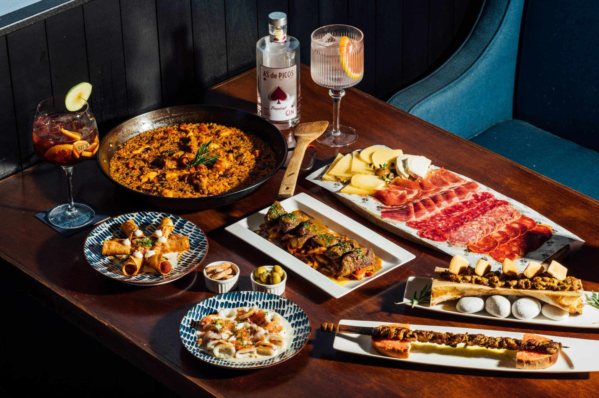 Grande table dressée : paella, planche de charcuterie, brochettes et verres de sangria